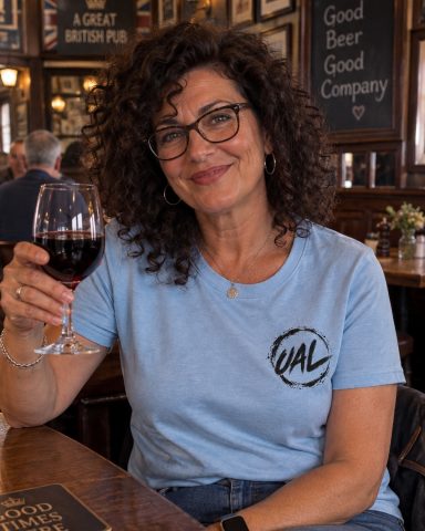 UAL Circular Logo T-Shirt – Light Blue Woman wearing light blue UAL T-shirt in a traditional British pub